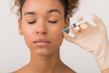 African-american woman getting face injection in clinic