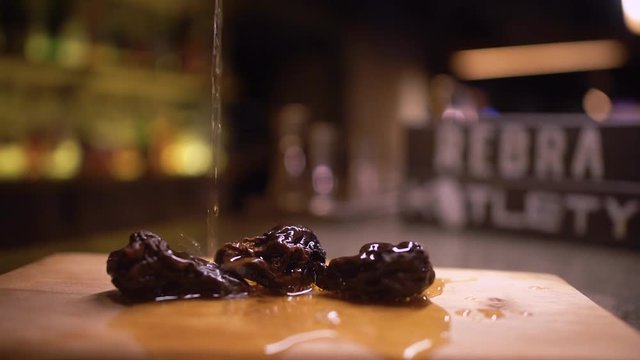 Dry fruits are pouring by alcohol on the wooden board close up