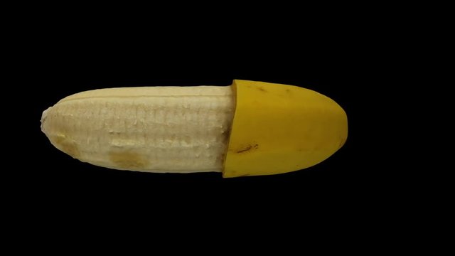 Realistic render of a rotating half peeled banana (Cavendish variety) on black background. The video is seamlessly looping, and the object is 3D scanned from a real banana.