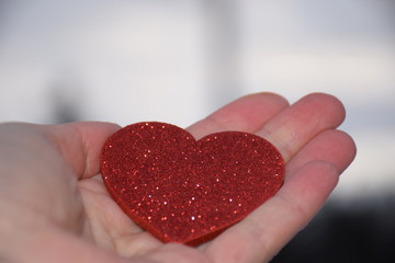 Red shiny heart in hand on white background. Red heart on a light background. St. Valentine's Day background. Empty place for text. Postcard and gift. Love concept. Valentine's Day