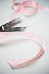 sewing scissors and pink satin ribbon isolated on white background