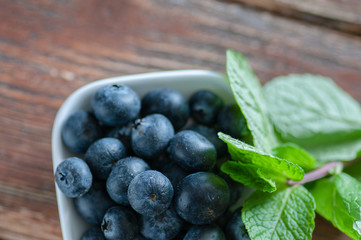 blueberries on a table in a white saucer and in an old cup