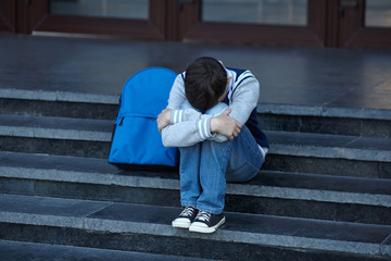 Schoolboy crying in the yard of the school