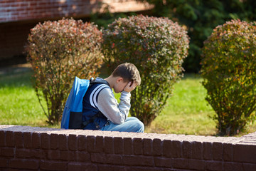 Fototapeta premium Schoolboy crying in the yard of the school