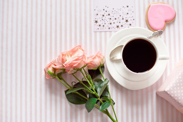 Valentine's day celebration with cup of coffee and valentines decoration on pink tablecloth texture background.