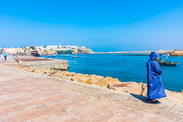Man wearing traditional blue clothes near the Ocean in Rabat, Morocco