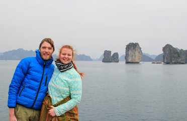 Fototapeta premium Young couple guy and girl in sportswear hugging and laughing happily against the background of the cliffs of Ha Long Bay during the honeymoon in Vietnam
