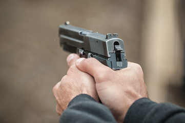 Shooter holding gun in hand and shooting. Close-up detail view