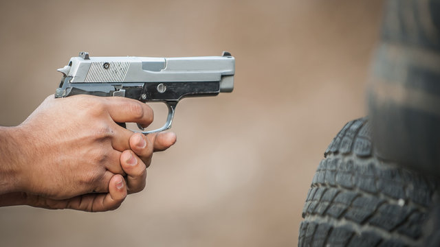 Shooter holding gun in hand and shooting. Close-up detail view