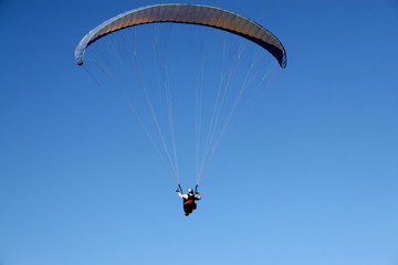 Paraglider in flight against the blue sky view from the back