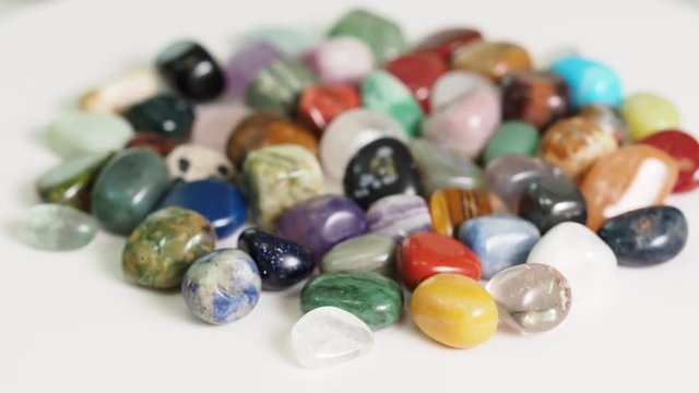 handful of various tumbled gemstones rotating on white table