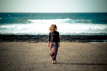 One woman walking at the beach to the ocean and waves enjoying the feeling of freedom and nature...