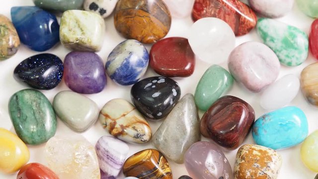 various gemstones rotating on white table close up
