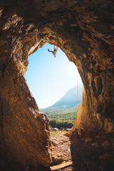 Rock climber climbs into the cave.