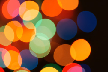 Multi-color holiday garland. Garland is blurred. Many colorful round lights. Fully defocused photo. Blurred background and foreground. Holiday mood. New Year and Christmas is coming.