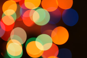 Multi-color holiday garland. Garland is blurred. Many colorful round lights. Fully defocused photo. Blurred background and foreground. Holiday mood. New Year and Christmas is coming.