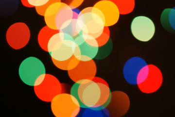 Multi-color holiday garland. Garland is blurred. Many colorful round lights. Fully defocused photo. Blurred background and foreground. Holiday mood. New Year and Christmas is coming.