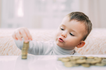 Fototapeta premium The child builds the tower of the coins closeup