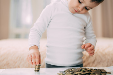 The child builds a coin tower on the table with a reflection