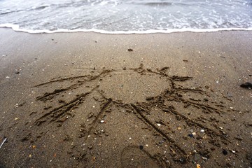 sun drawing on sand and sea