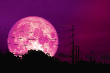 full pink moon floats in night sky above the shadow of an electric pole