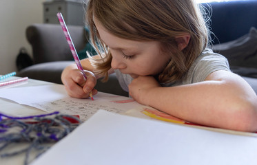 female child drawing and writing on the lounge table