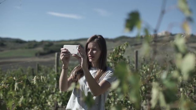 Young woman  takes pictures in the vineyard