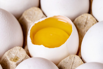 White and brown eggs in carton with broken egg.White chicken eggs in a cardboard package. Healhy...