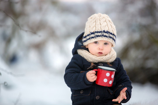 Sweet siblings, children having winter party in snowy forest.  Young brothers, boys, drinking tea from thermos. Hot drinks and beverage in cold weather