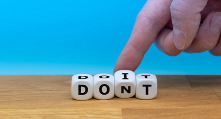 Hand turns dice and changes the word "don't" to "do it". Personal change yourself concept.
