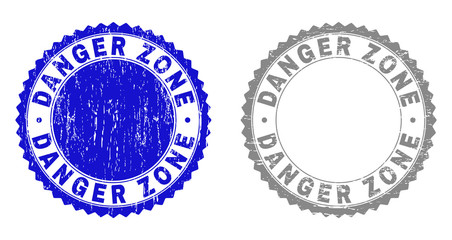 Grunge DANGER ZONE watermarks isolated on a white background. Rosette seals with grunge texture in blue and gray colors. Vector rubber stamp imprint of DANGER ZONE title inside round rosette.