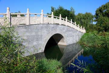 Fototapeta na wymiar Archaize stone bridge in the park