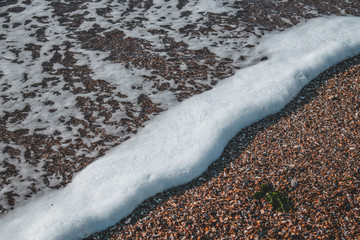Beautiful background of natural looking sea and sand with green seaweed, sea foam kissing the beach