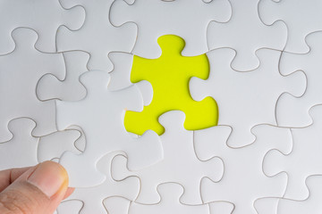 Fototapeta premium Hand put the last piece of jigsaw puzzle closeup to complete the mission. Selective focus and crop fragment