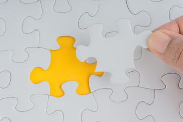 Obraz premium Hand put the last piece of jigsaw puzzle closeup to complete the mission. Selective focus and crop fragment