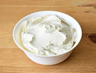 Cream cheese, quark or yogurt in a white bowl. Dairy product, healthy eating theme. wooden table background.