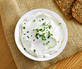 Cream cheese, quark or yogurt in a white bowl. Dairy product with fresh herbs, healthy eating...