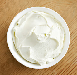 Cream cheese, quark or yogurt in a white bowl. Dairy product, healthy eating theme. wooden table background.