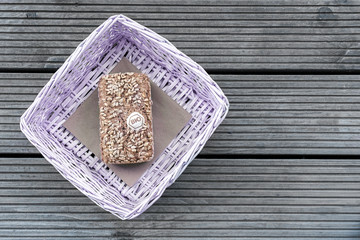 A loaf of bread lies in a lilac basket on a wooden table.