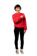 Fototapeta premium A full-length shot of a Short hair girl with red sweater pointing to the side to present a product over isolated white background
