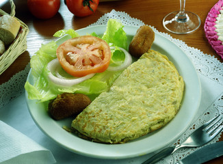 Plato con media tortilla de patatas, ensalada y croquetas.