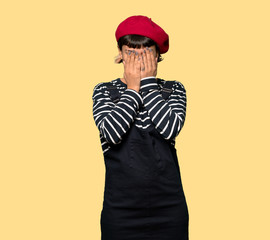 Young woman with beret with tired and sick expression over yellow background