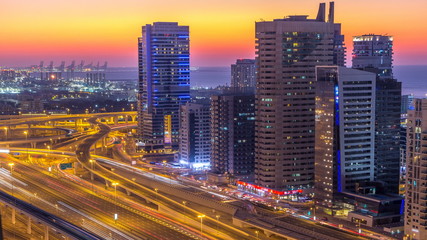 Naklejka na ściany i meble Dubai marina with traffic on sheikh zayed road panorama day to night timelapse lights turn on.