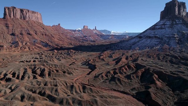 Aerial view flying over eroded desert towards Castleton Tower past Parriott Mesa in the old west desert terrain near Moab Utah.