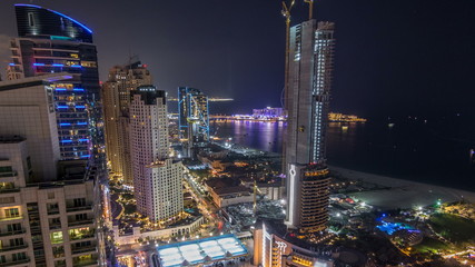 Fototapeta premium Aerial view of modern skyscrapers and beach at Jumeirah Beach Residence JBR night timelapse in Dubai, UAE