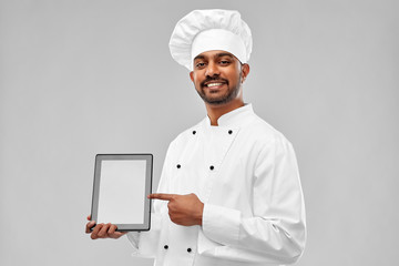 cooking, technology and people concept - happy male indian chef in toque with tablet computer over...