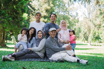 portrait of family with parent, grandparent and grandchildren together relaxing in the park