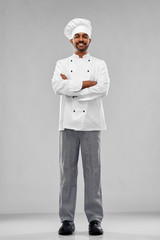 cooking, profession and people concept - happy male indian chef in toque over grey background