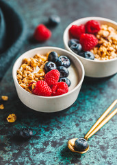 Vegetarian breakfast, a bowl with organic granola, fresh raspberries and blueberries and coconut yoghurt.