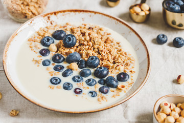 Healthy breakfast, a bowl with organic granola, chocolate pieces, fresh blueberries, hazelnuts and soya milk.